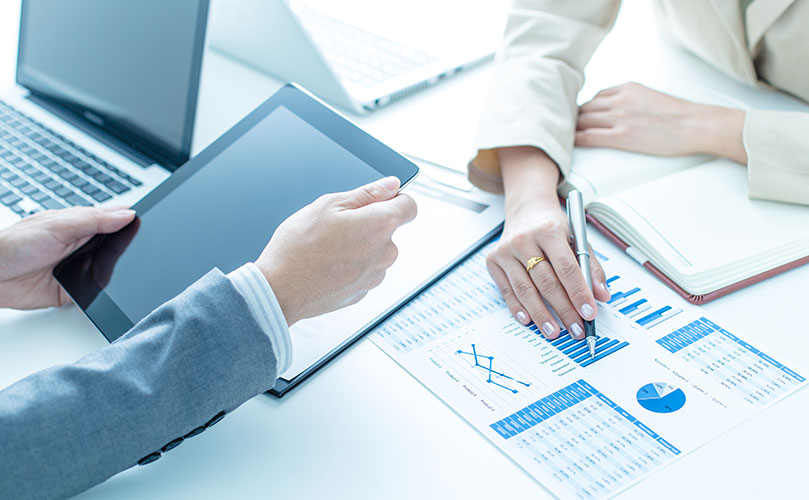 タブレットと書類を使ってビジネスデータを分析し、協力している人々。