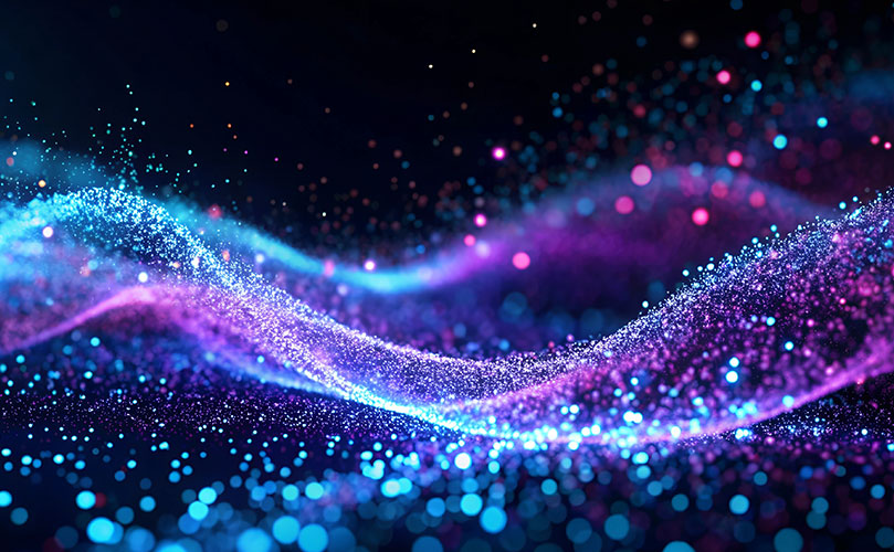 青と紫の光の粒子が波のように流れる抽象的な背景。