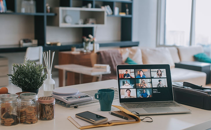 在宅勤務で、リビングに置かれたノートパソコンでビデオ会議をする様子。