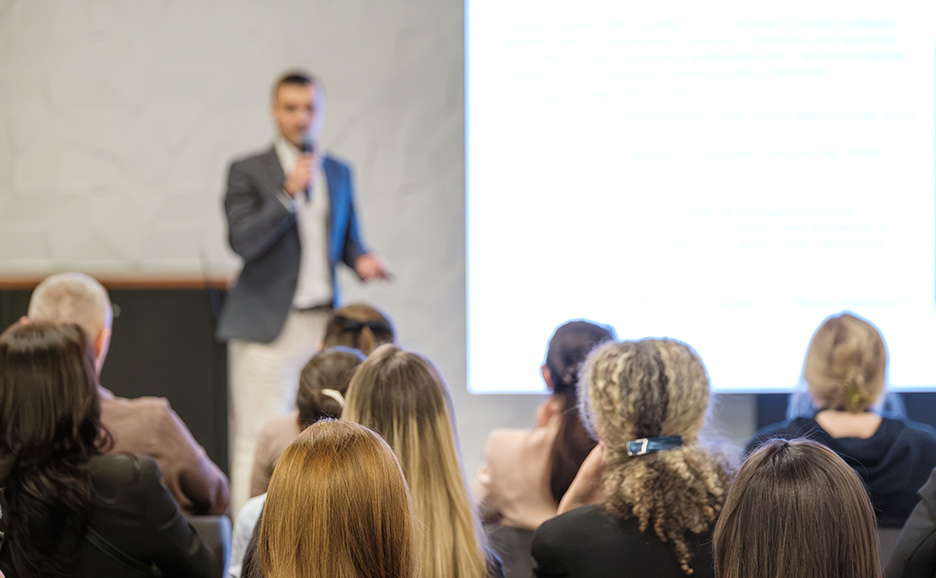 会議場で講演する男性と聴衆