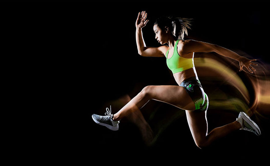 Athlet in dynamischem Sprungsprint vor dunklem Hintergrund mit leuchtenden Bewegungseffekten