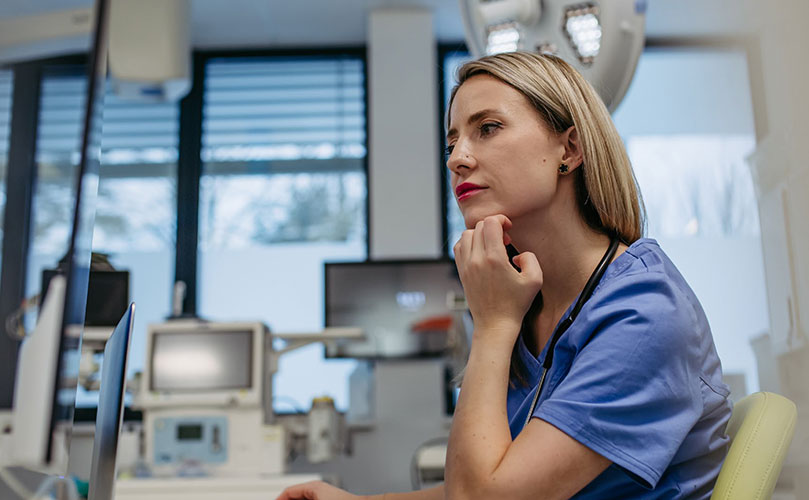 Female medical professional in scrubs looking thoughtful.