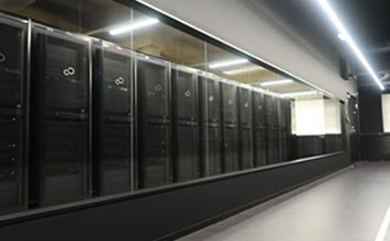 サーバーラックが並び、ガラスで仕切られたサーバールームの風景。