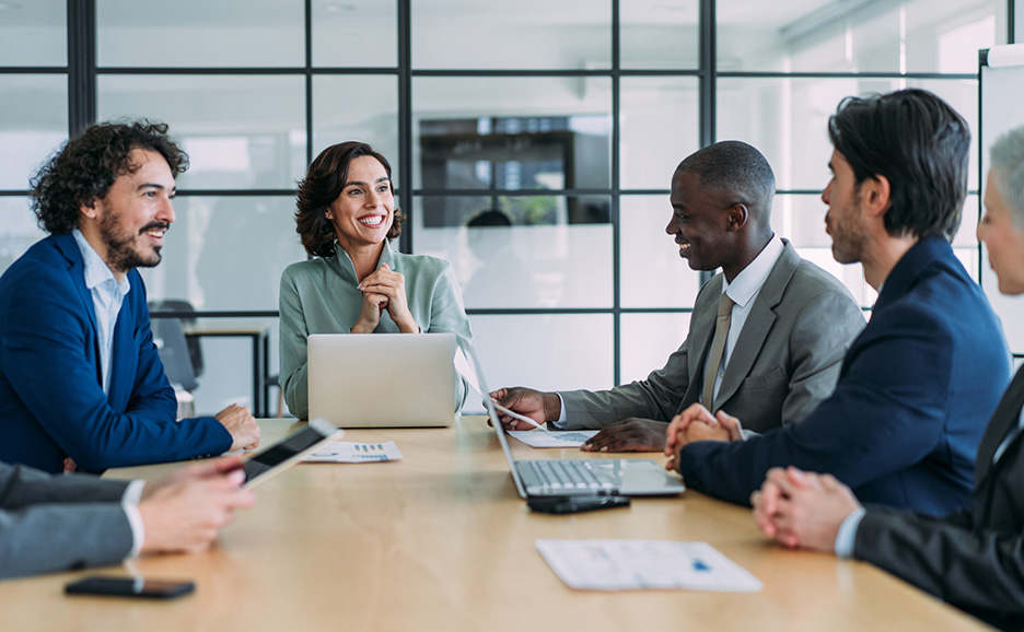 Business people smiling and discussing around a laptop in a meeting room