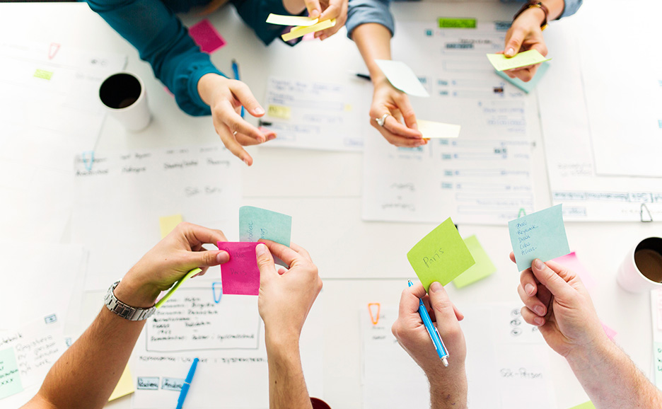 テーブルの上で付箋を使いながらアイデアを出し合う人々