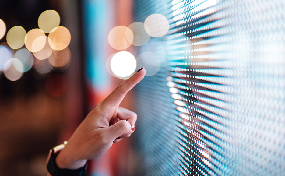 A hand touching a bright LED scree
