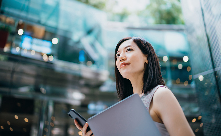 ラップトップと携帯電話を持つ屋外の女性