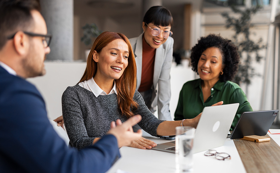 Diverse business professionals actively discussing around a laptop in a meeting