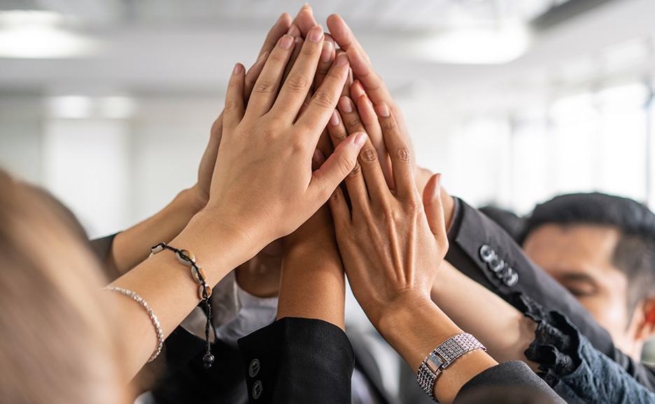 Multiple hands high-fiving, symbolizing teamwork and collaboration
