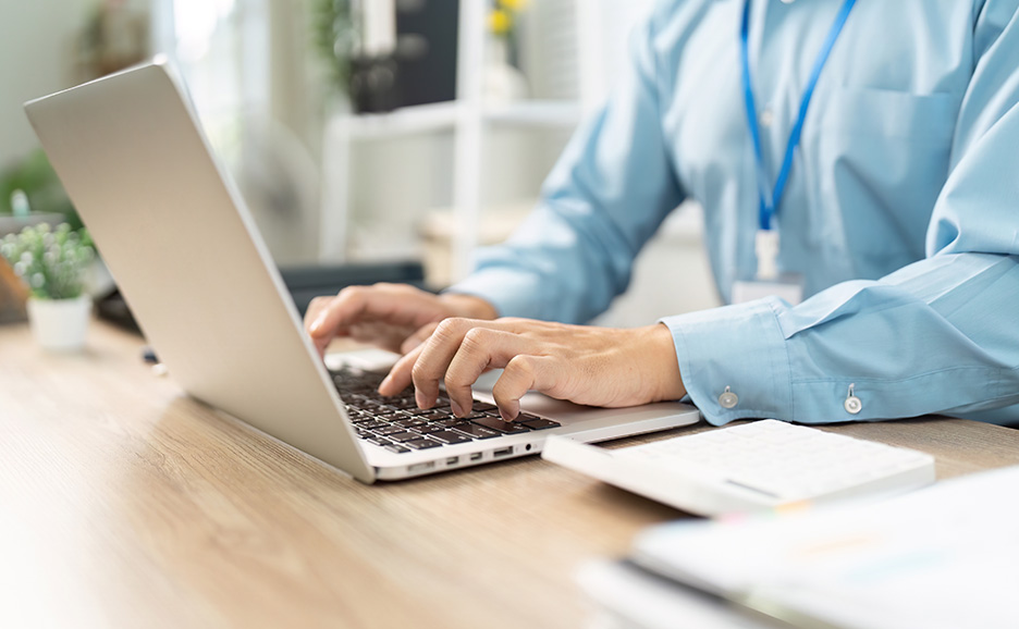 Close-up of a business person operating a laptop in an office