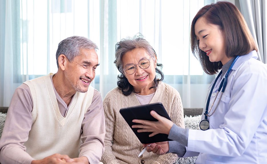Doctor and elderly couple talking, looking at a tablet