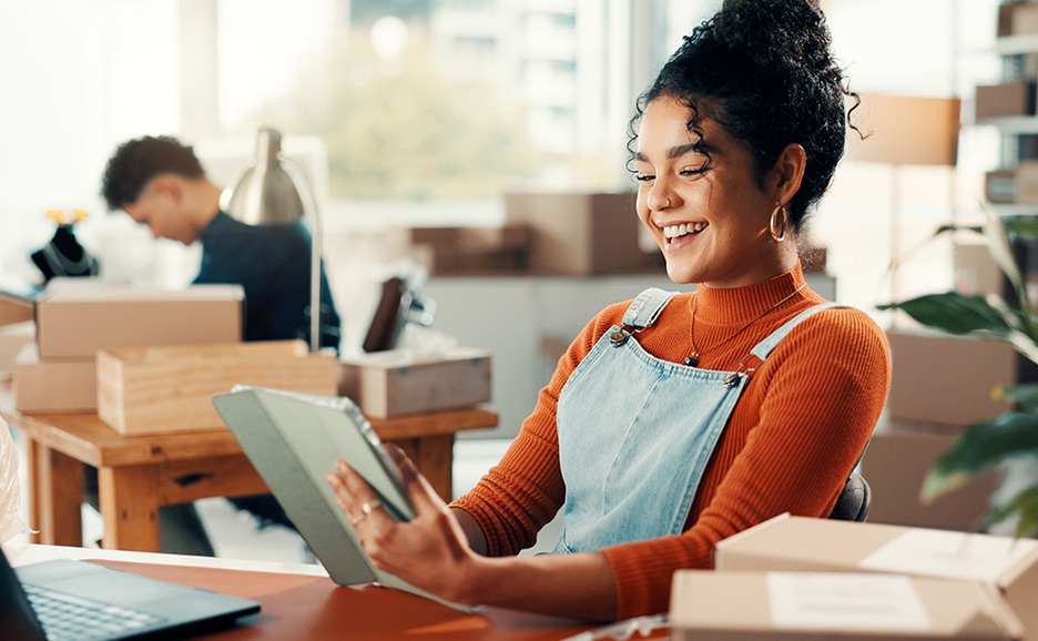 机でタブレットを見ながら微笑む若い女性