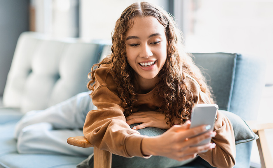A young woman looking at her smartphone on a sofa
