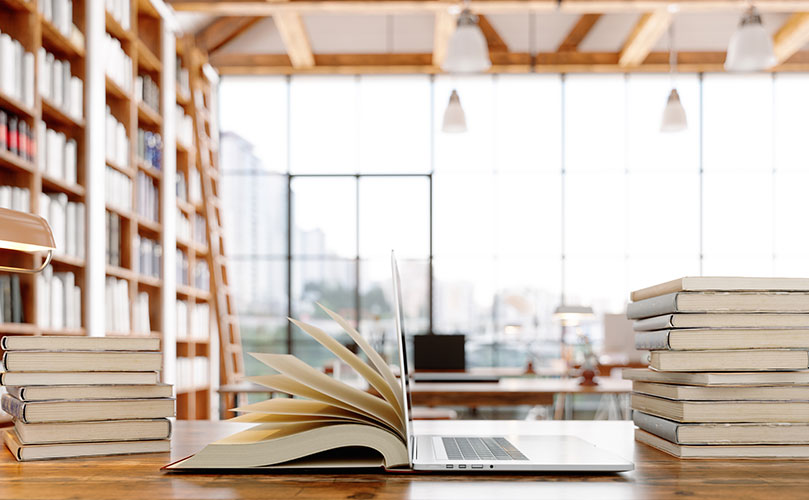 図書室の机の上にある本とノートパソコン