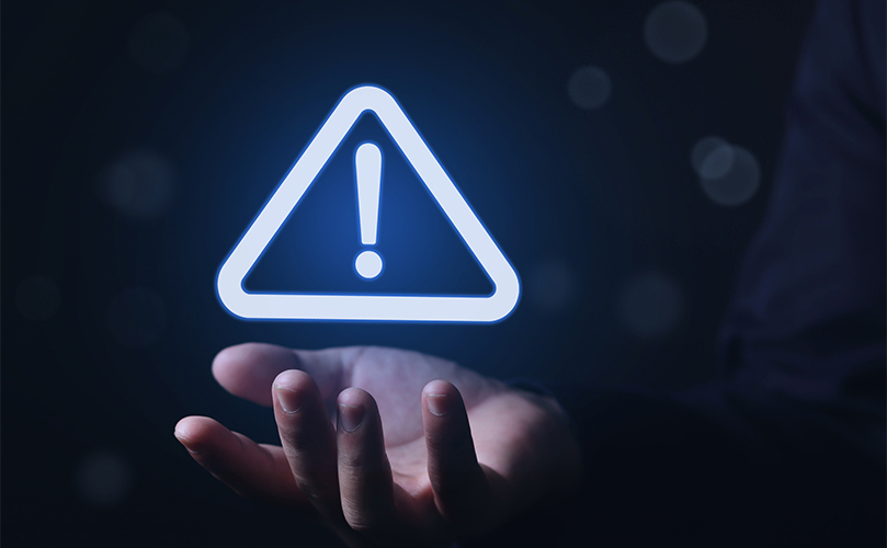 Alert symbol above a hand