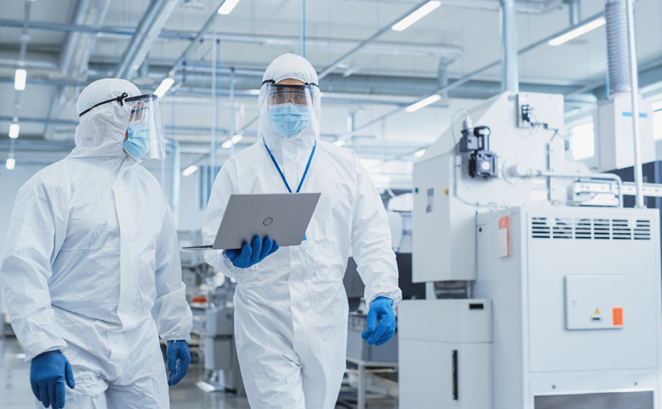 製薬工場を歩きながら会話する二人の科学者