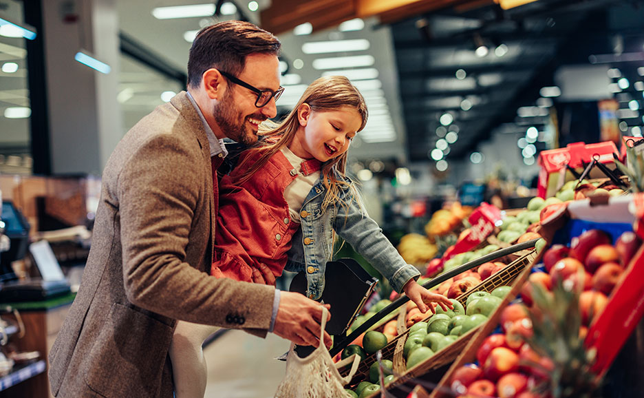 お父さんと娘がスーパーで笑顔でリンゴを選んでいる様子