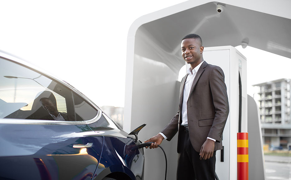 笑顔で電気自動車を充電するビジネスマン