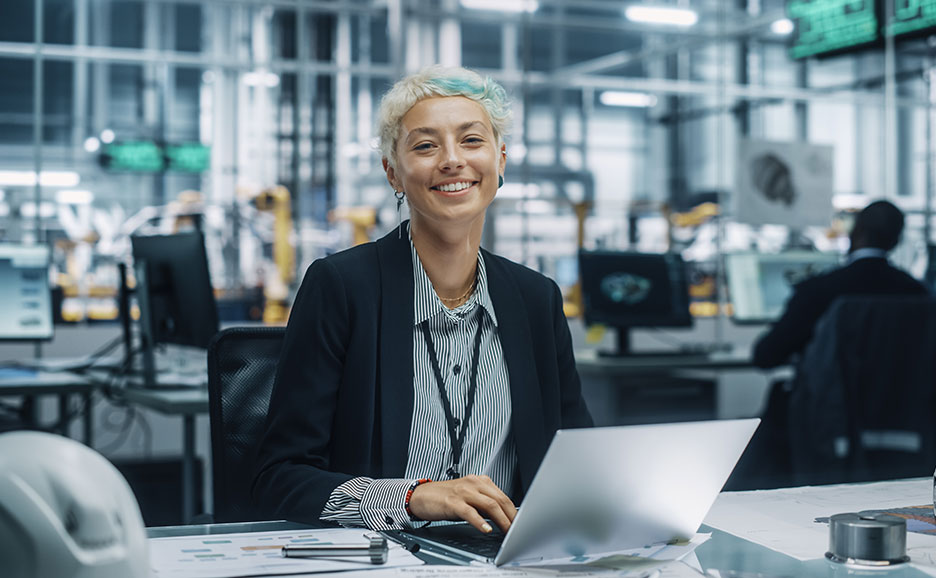 笑顔の女性エンジニアがノートPCで作業