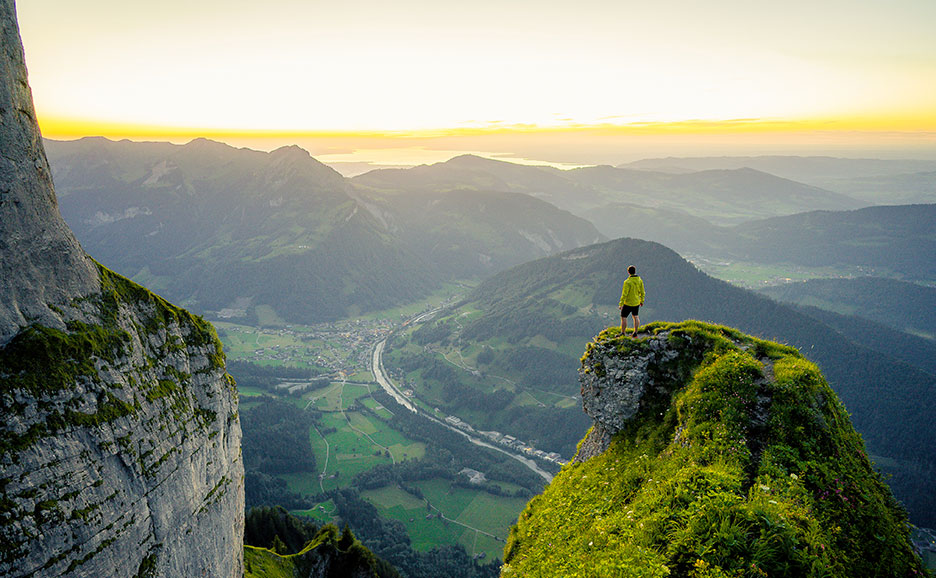 山頂から広がる壮大な夕焼けの景色を眺める男性