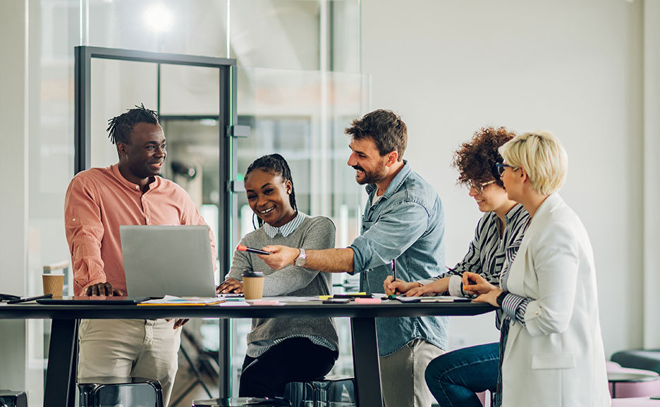 ノートパソコンを囲み共同作業をしている5人のビジネスチーム