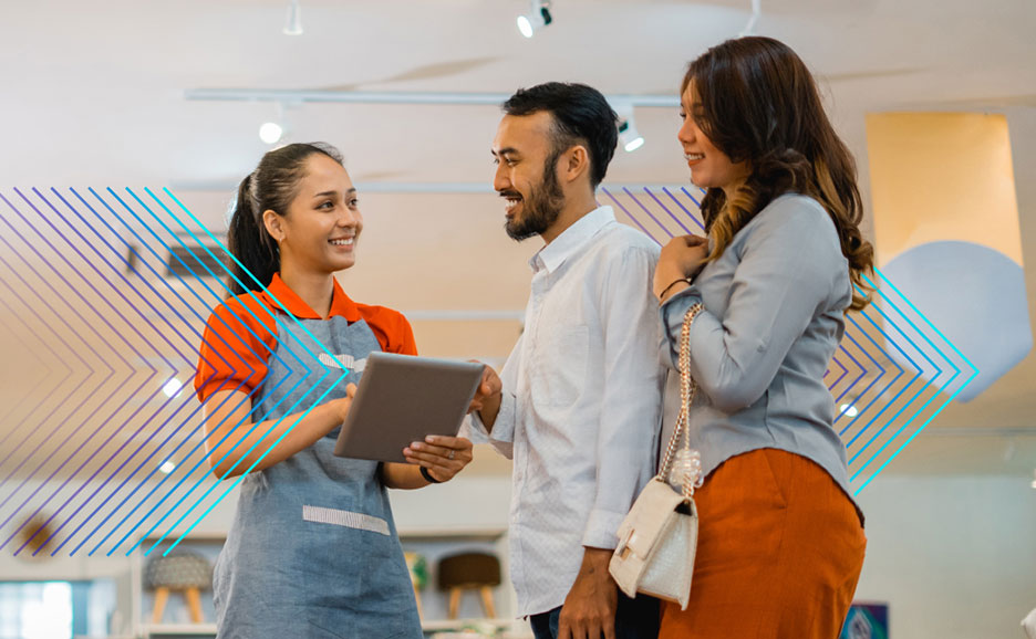店舗でタブレットを使い顧客対応する店員とカップル