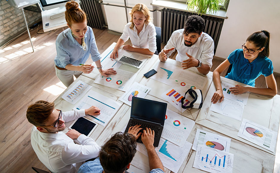 オフィスで書類を囲んで議論するビジネスパーソンたち