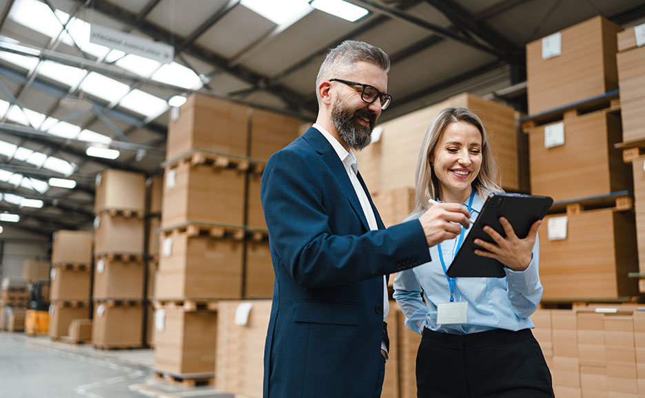 倉庫でタブレットを見ながら話す男女