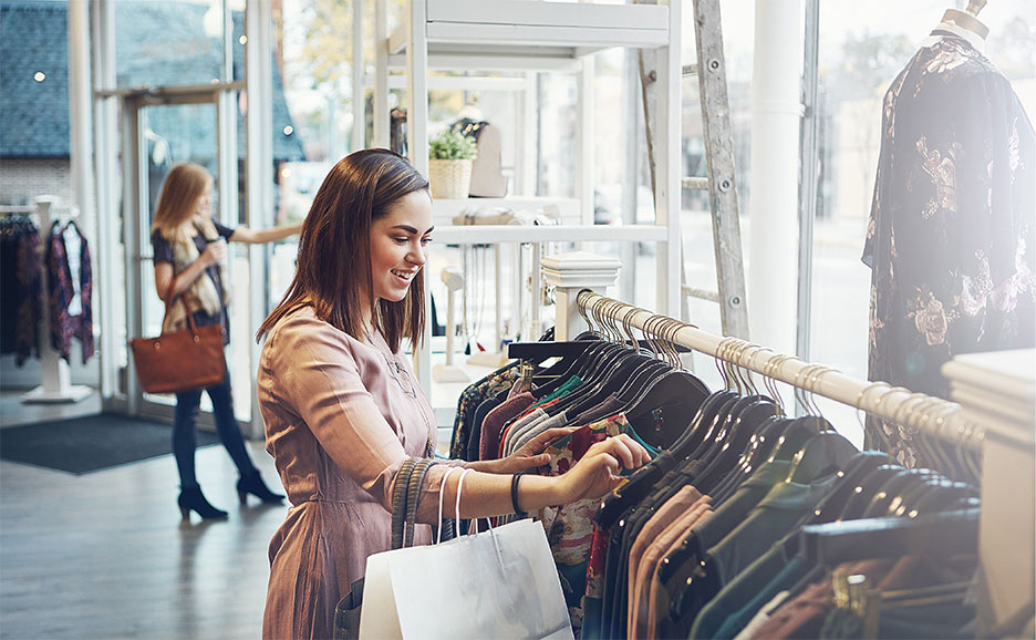 洋服店の棚から服を選んでいる女性たち