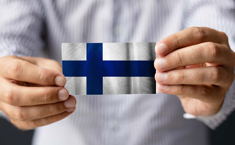 Henkilö pitelee pientä Suomen lippua 