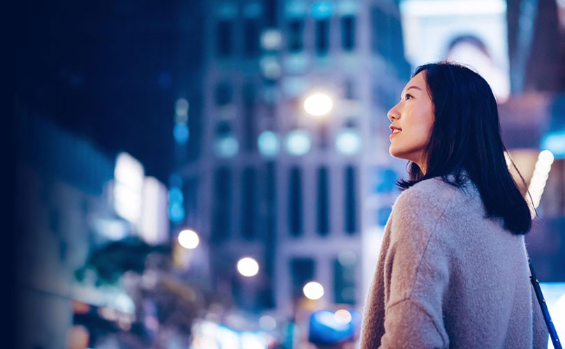 一个女人站在街上，沉思地看着外面的东西。