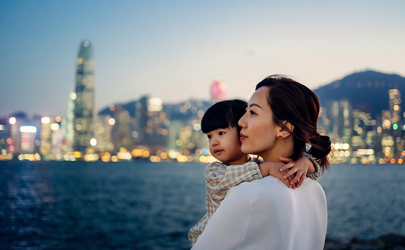娘を抱いて都市の風景を眺めている若い母親