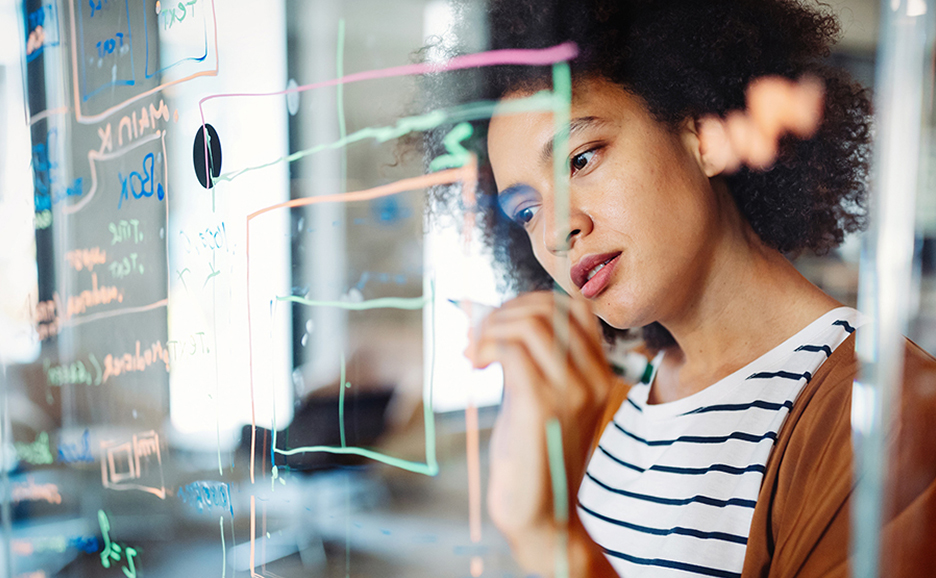 女性がガラスボードに図を描き、思考を整理