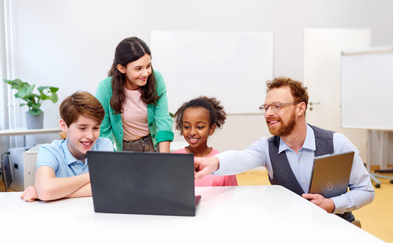 ラップトップを囲む教師と生徒たち