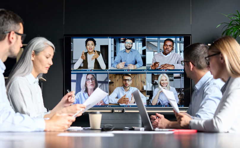 Business professionals engaged in a video conference within a modern meeting room setting.