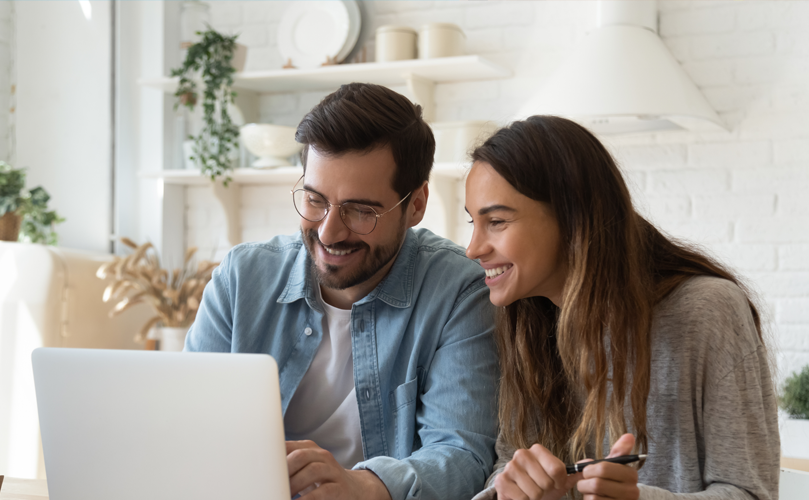 Two people laughing and looking at a computer