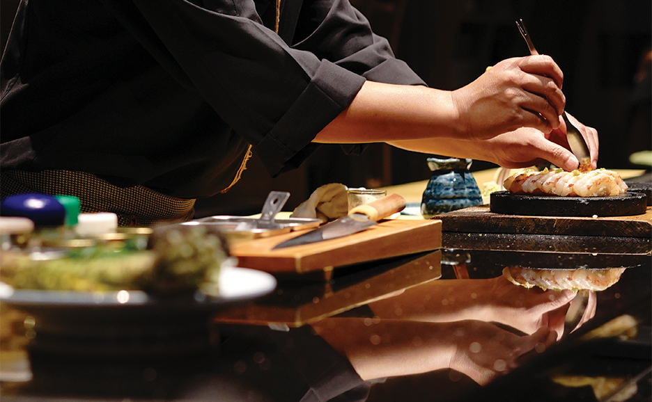 A chef is engaged in the preparation of sushi on a table