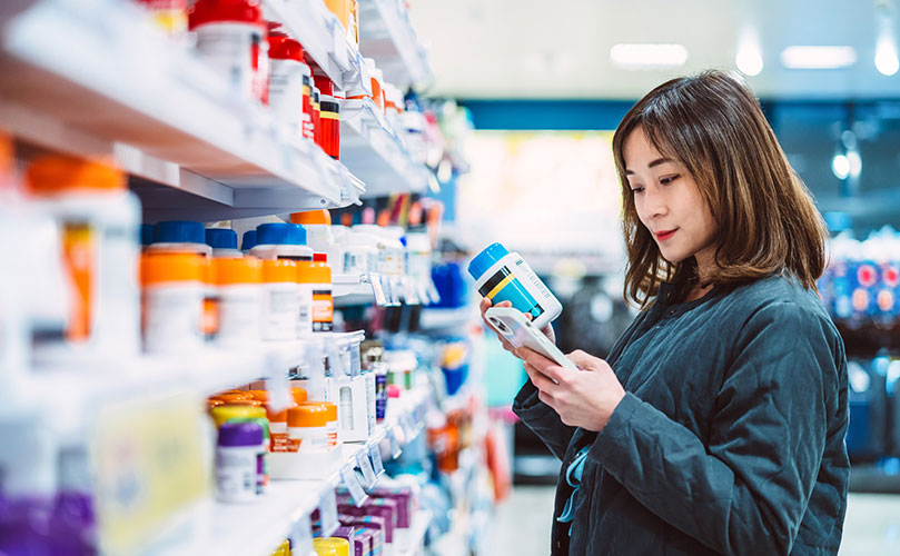 ドラッグストアで商品を選ぶ女性
