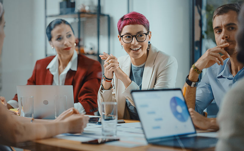 A diverse group of professionals engaged in a video conference in a modern meeting room.