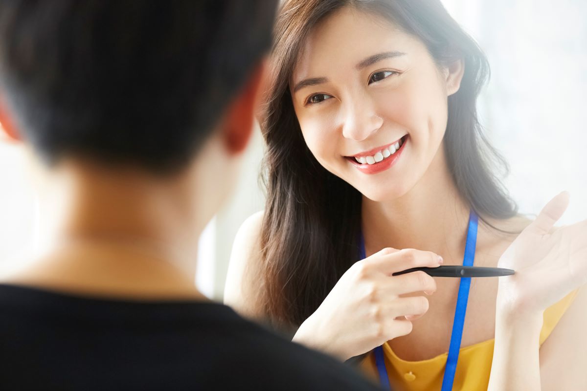 1on1の対面ミーティング 手前は後ろ姿の人物 奥の女性は笑顔で会話している