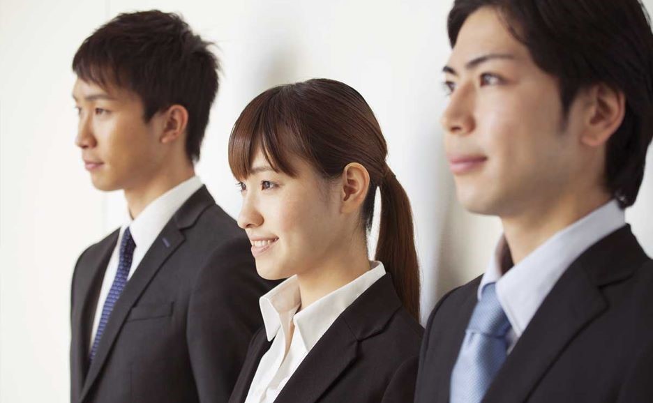 3人の若い社員 緊張感と笑顔の表情が混ざりながら遠くを見つめている