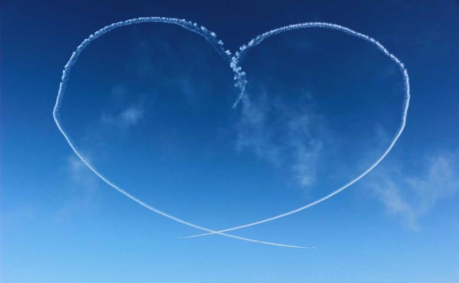 青空に飛行機雲で描かれるハートマーク