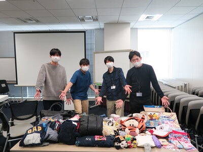 参加メンバーが４人並んで、寄付物品を紹介している