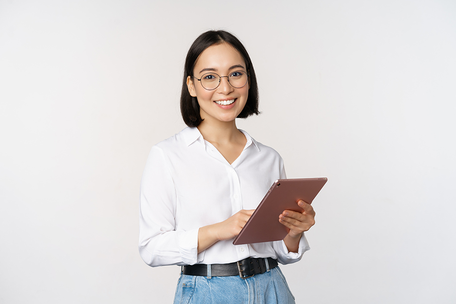 A bespectacled Asian woman holding a tablet and smiling at us