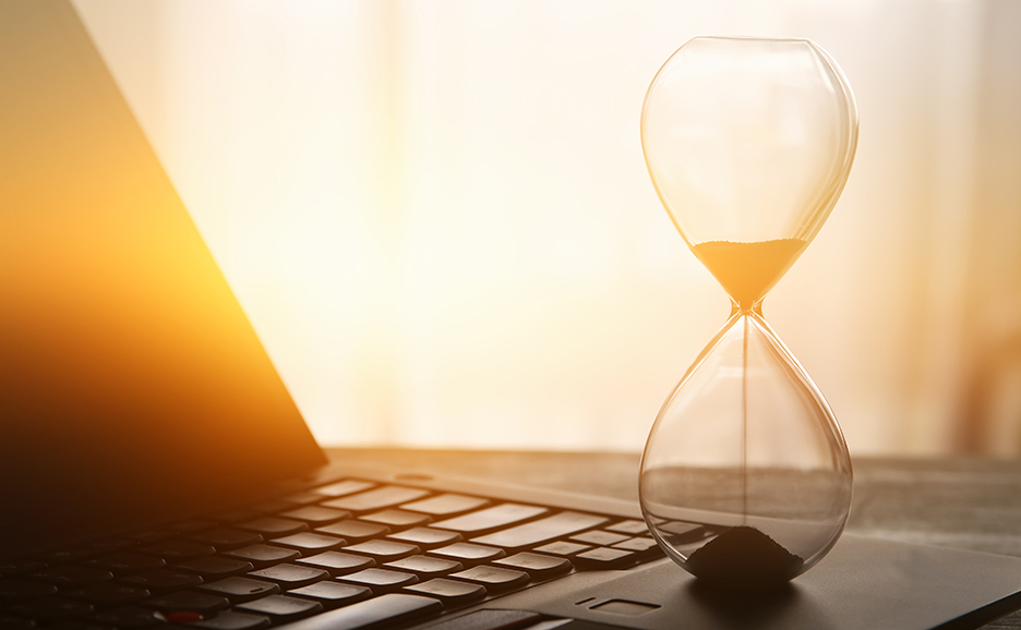 夕暮れ時のデスク,ノートPCの上に置かれた砂時計