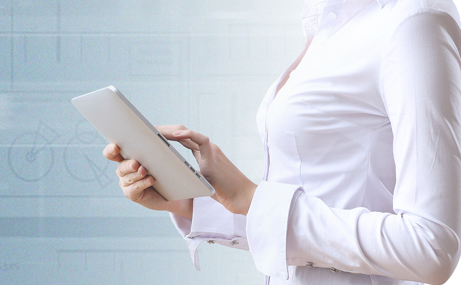 白いシャツを着た女性が、未来的な背景の前でデジタルタブレットを使用している。