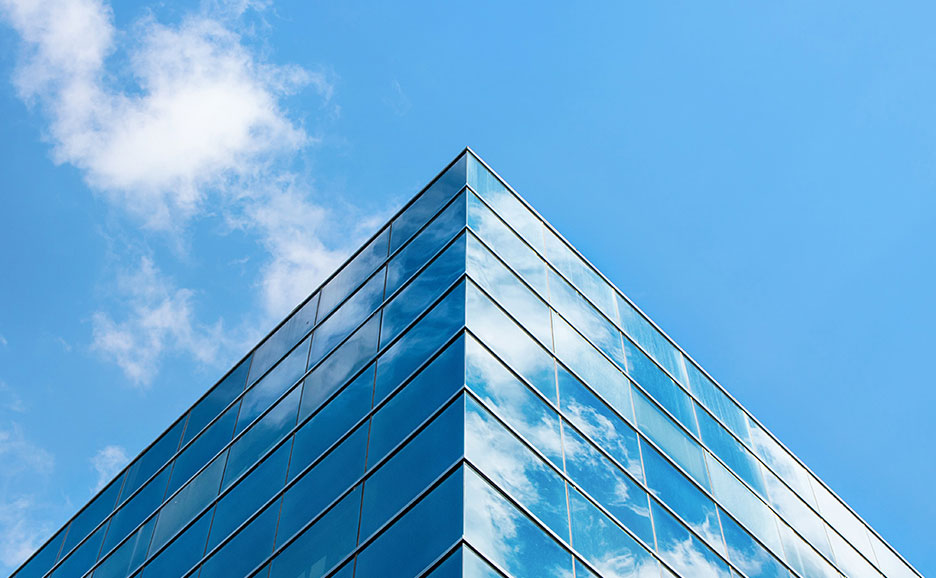 青空を背景に、ガラス張りの建物の角が映る