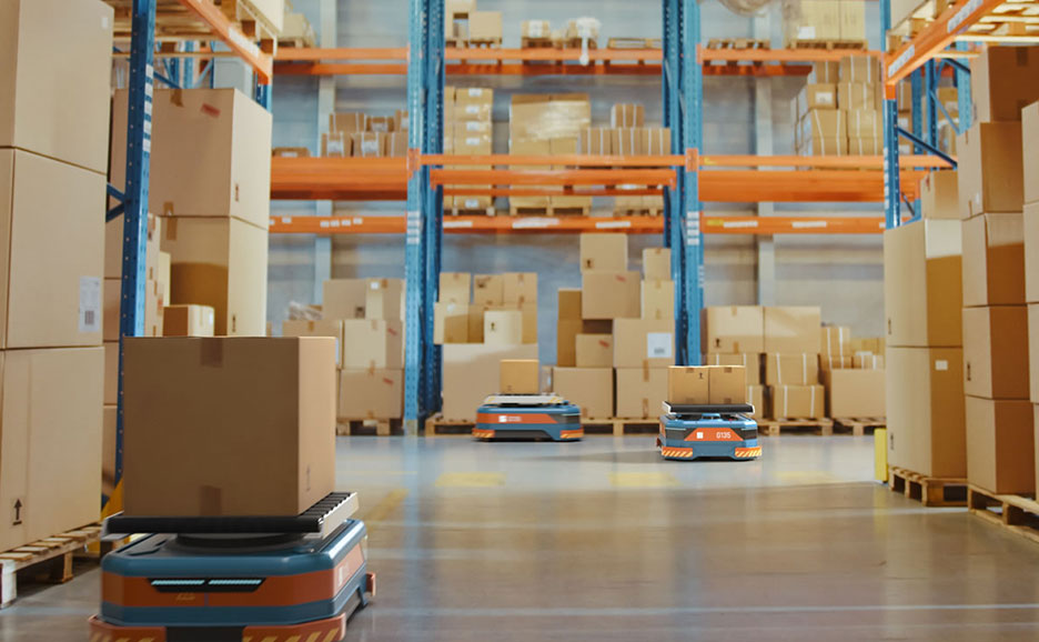 荷物を積んだ3台の自律移動ロボットが、倉庫の通路を移動している