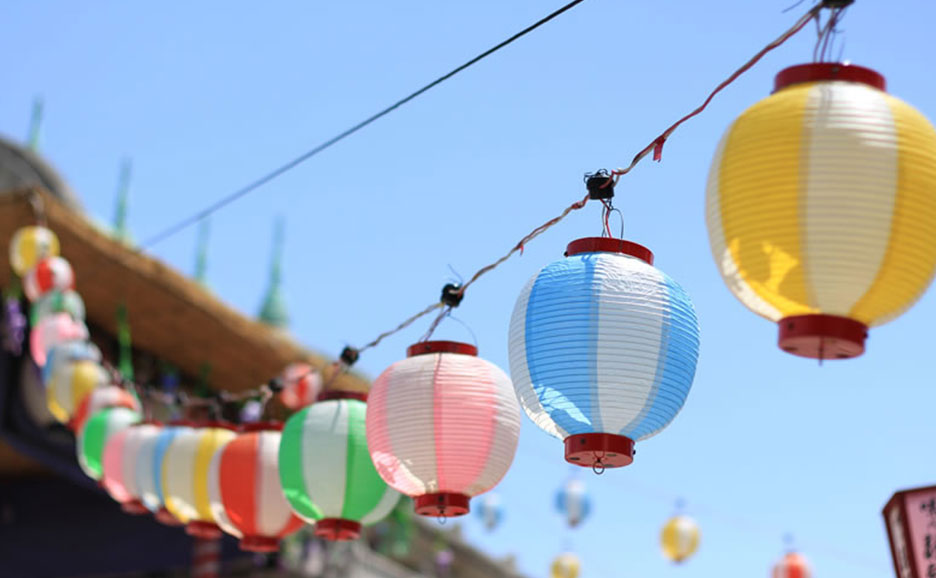 晴れた青空の下、カラフルな提灯がぶら下がっている。日本の夏の風景。
