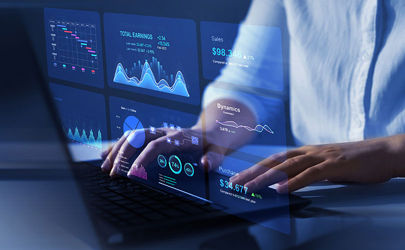 ビジネスパーソンがノートパソコンのキーボードを打ち、目の前に浮かぶ半透明のビジネスレポートのダッシュボードを操作している様子。